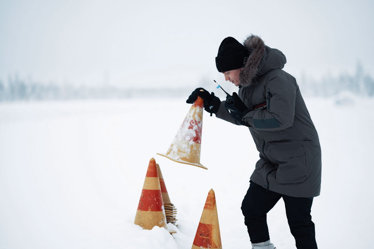 Man places cones alongside snowy track on Porsche Ice Experience