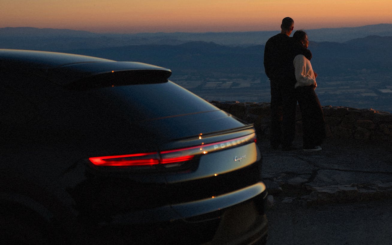 Julie Sariñana, aka Sincerely Jules, with husband overlooking LA at dusk, with Porsche Cayenne coupé (E3) in the foreground