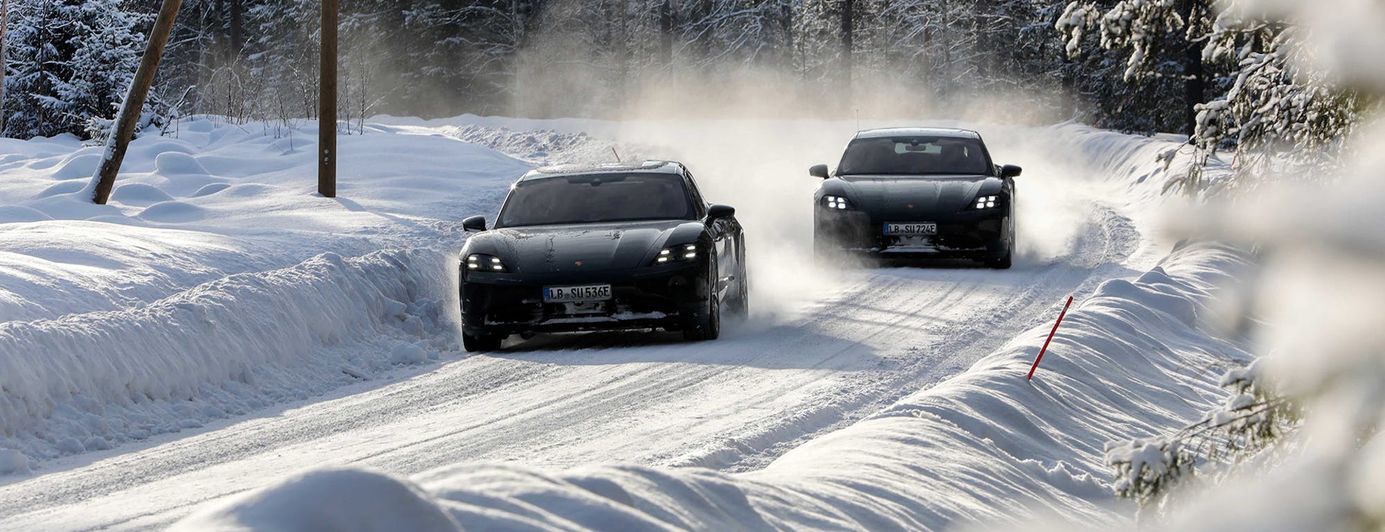 Two black Porsche Taycan cars in snow