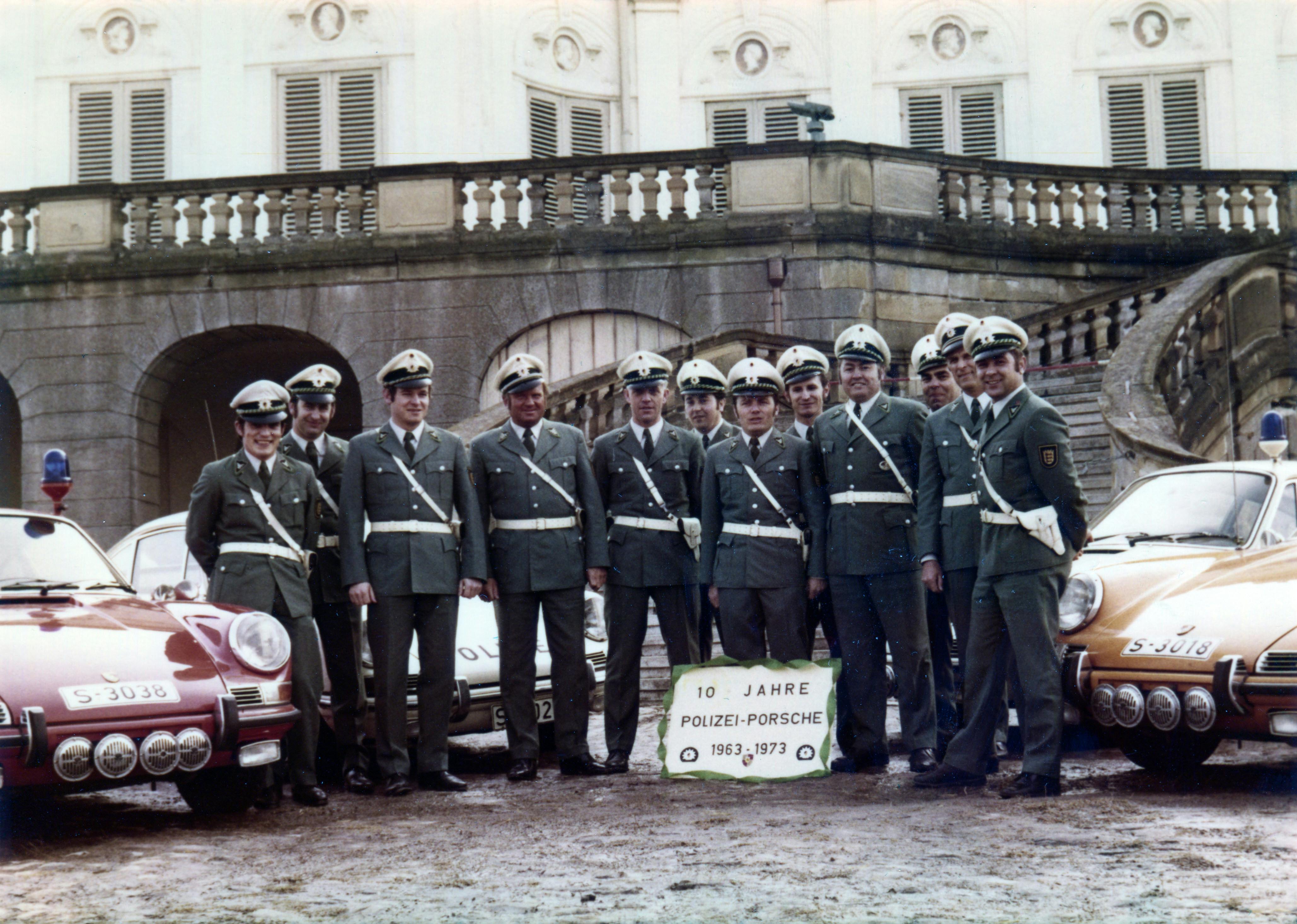 Group of police officers standing with Porsche police cars