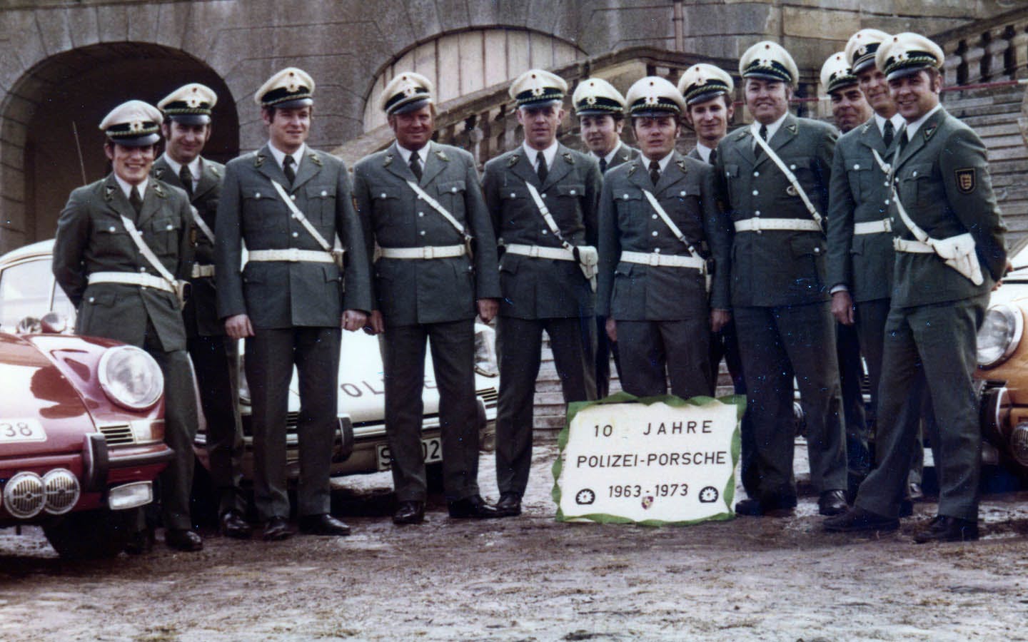 Group of police officers standing with Porsche police cars