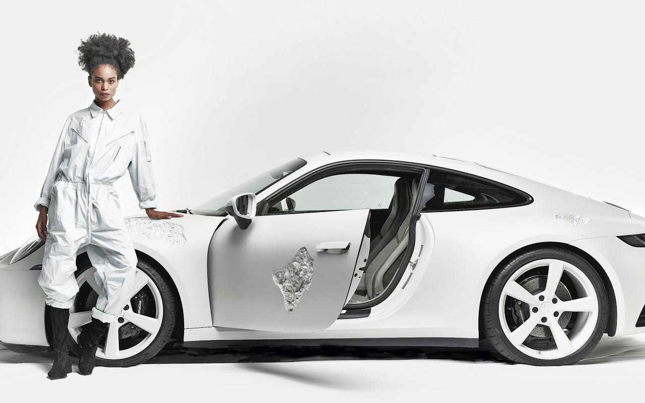 Side view of the white, Crystal-eroded 911 with women leaning on hood