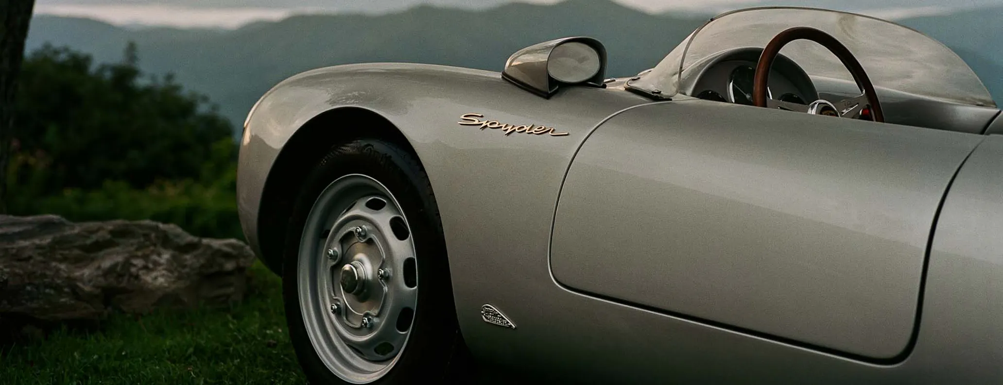 Front, side view of Porsche 550 J parked with mountains in background