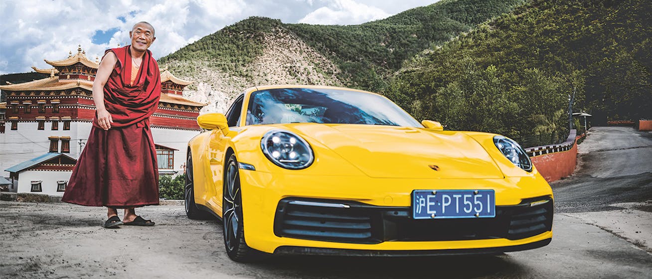 Tibetan Buddhist monk standing next to yellow Porsche 911