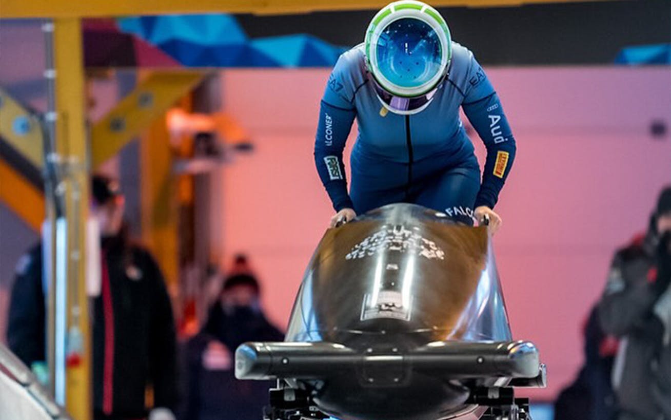 Woman in racing suit pushing a bobsleigh 