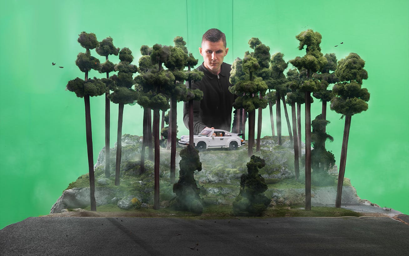 Man standing behind miniature forest diorama