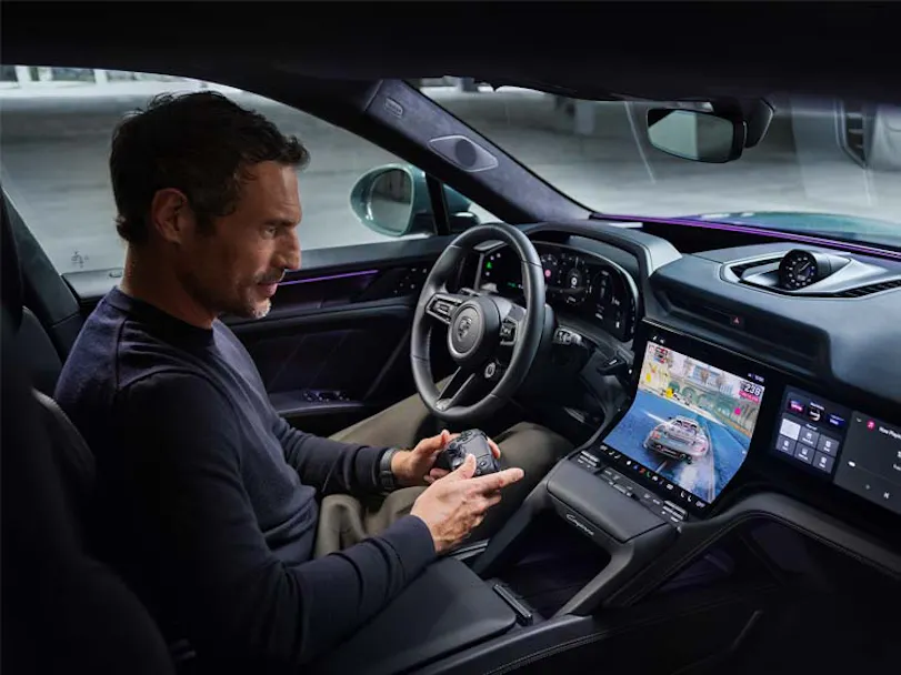 Man playing games inside car on Porsche Cayenne Electric large central display thumbnail