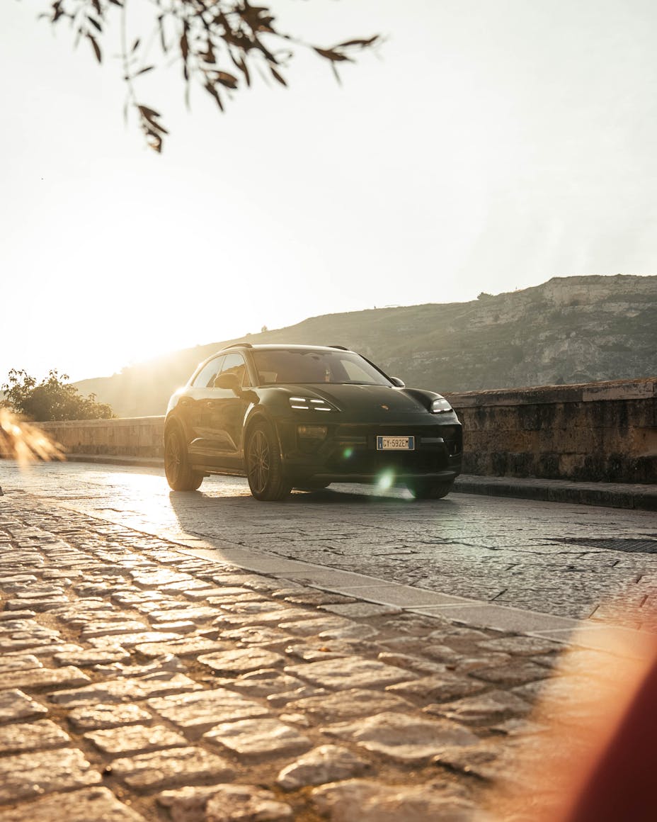 Porsche Macan 4S Electric parked on cobblestones under sun in Italian village