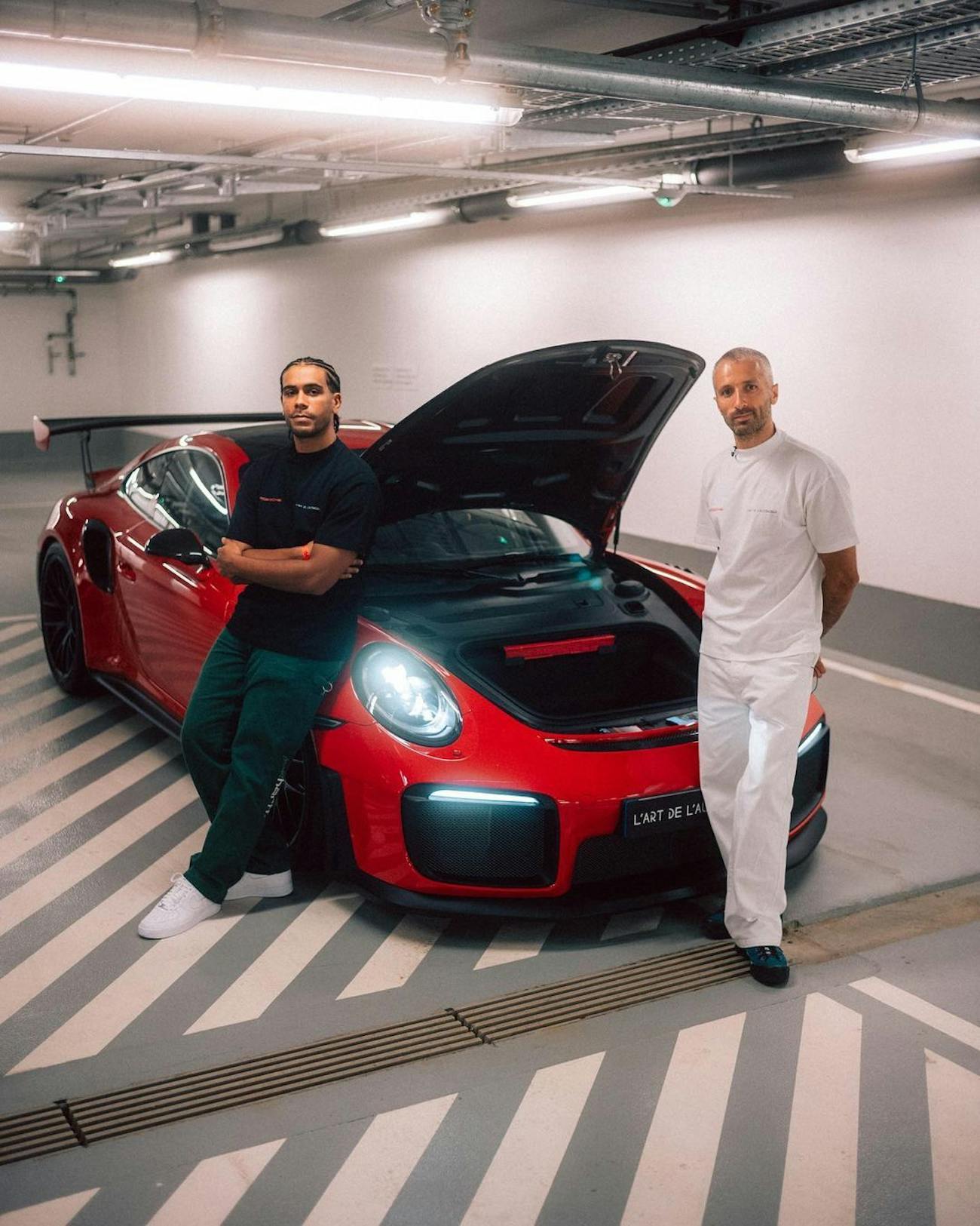 Two men inside a garage besides Porsche with hood open