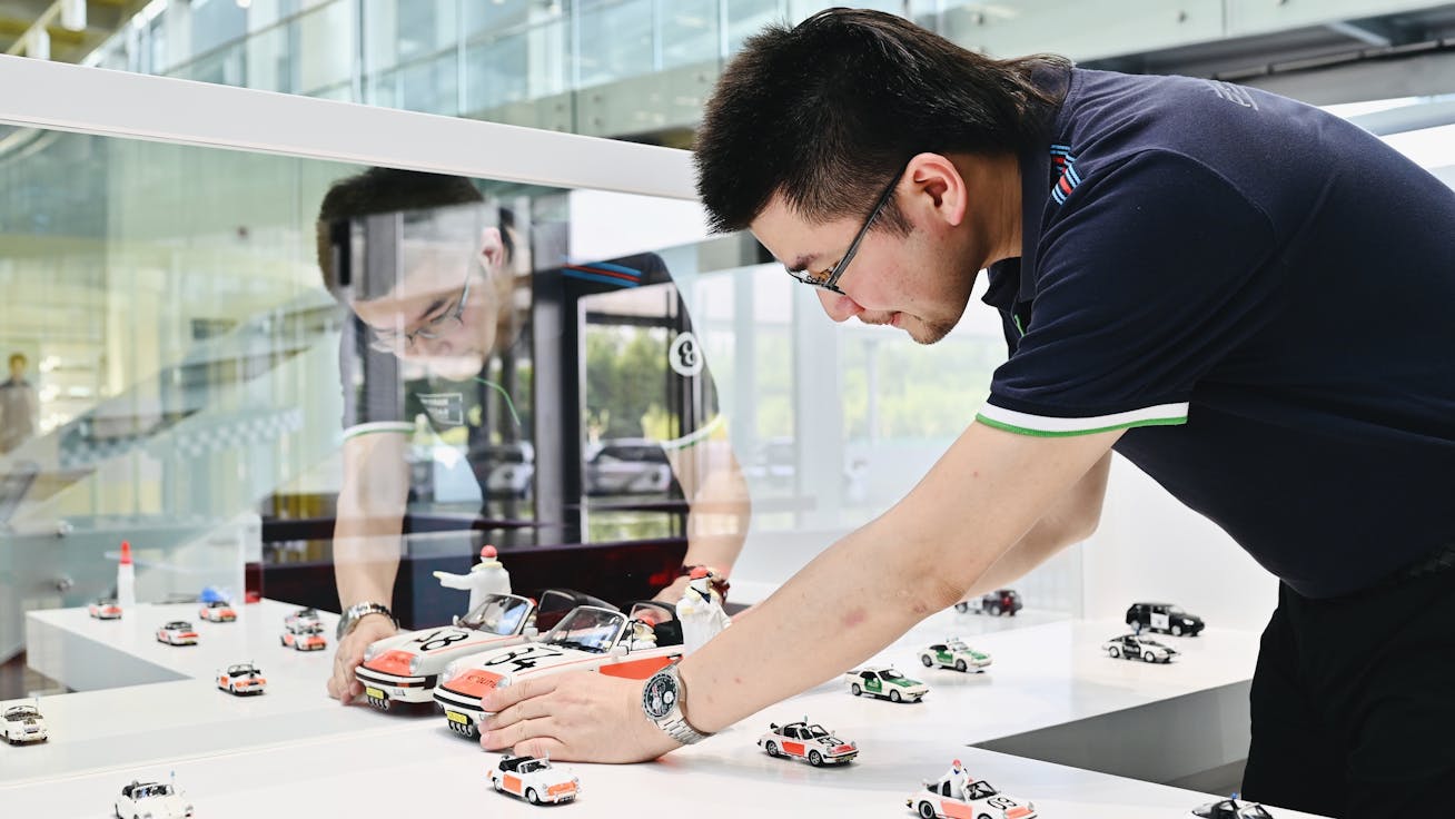 Man places model of Porsche in a model car display