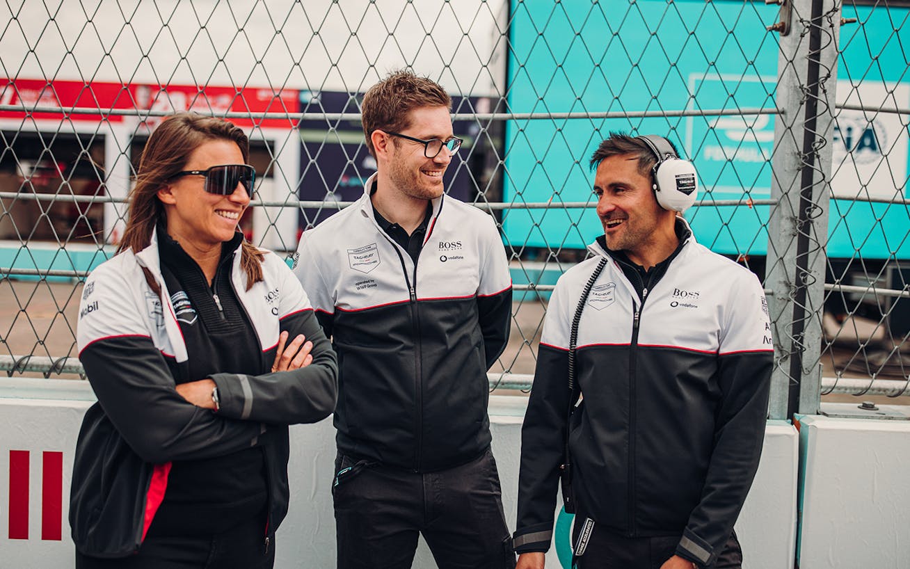 Two men and a woman talking by side of racetrack 