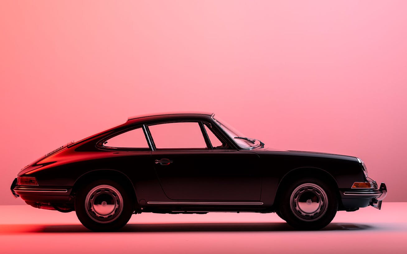 Classic Porsche 911 parked in studio with pink background