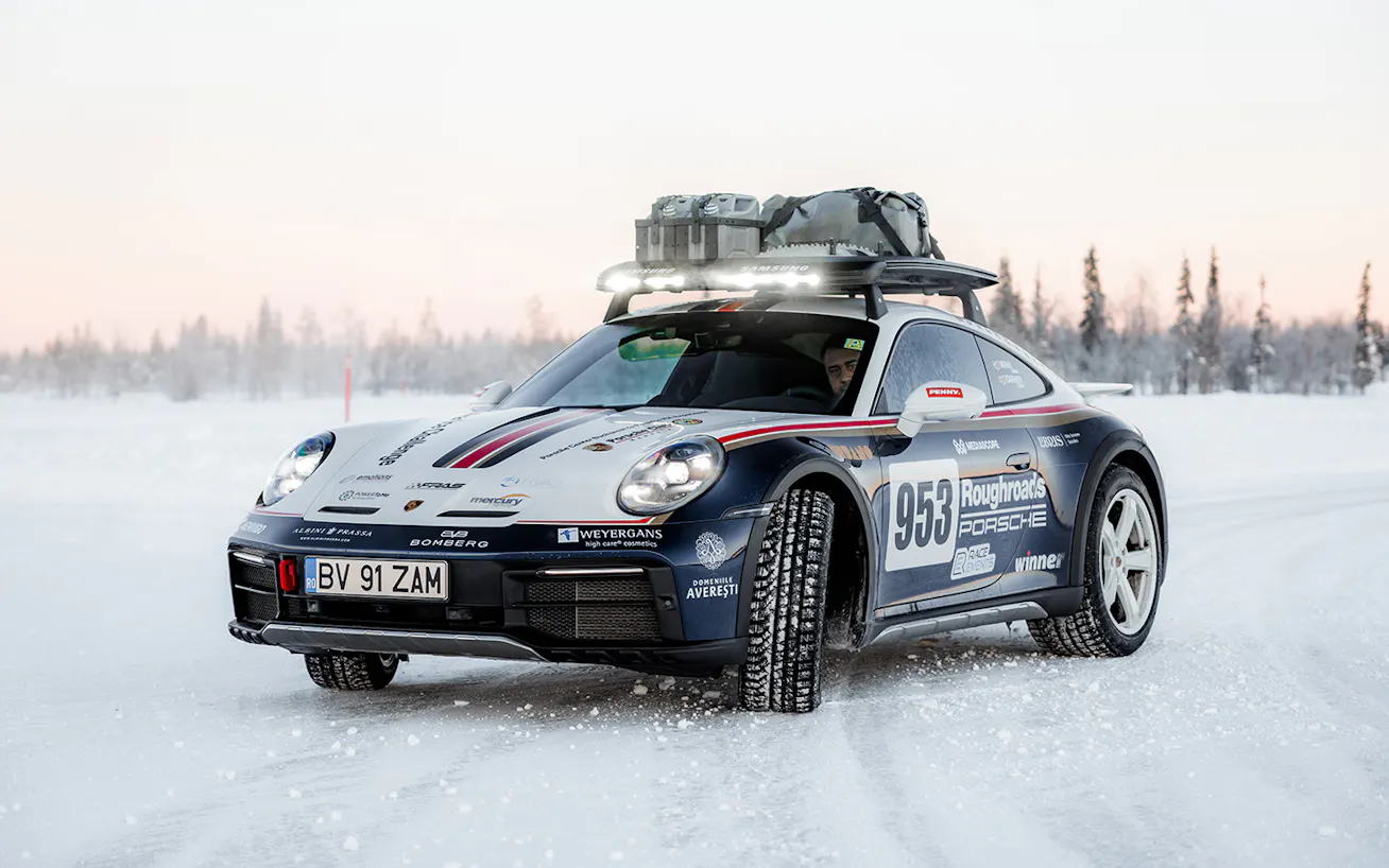 Front view of a Porsche 911 Dakar drifting on a snowy road