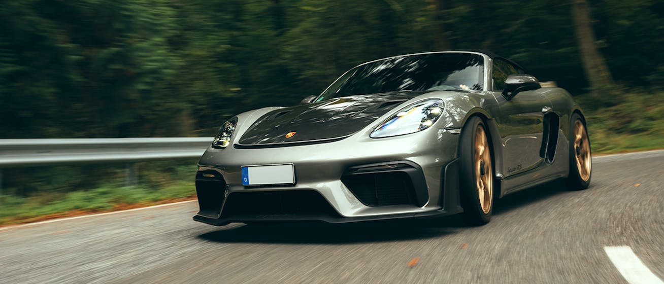 Grey Porsche 718 Spyder RS driving on forest road