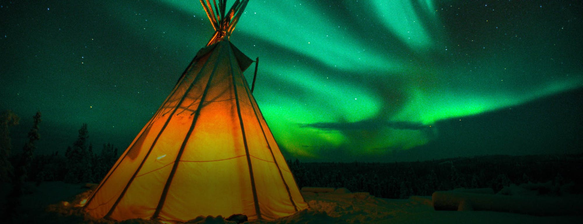 Teepee lit up in snow, Northern Lights in sky