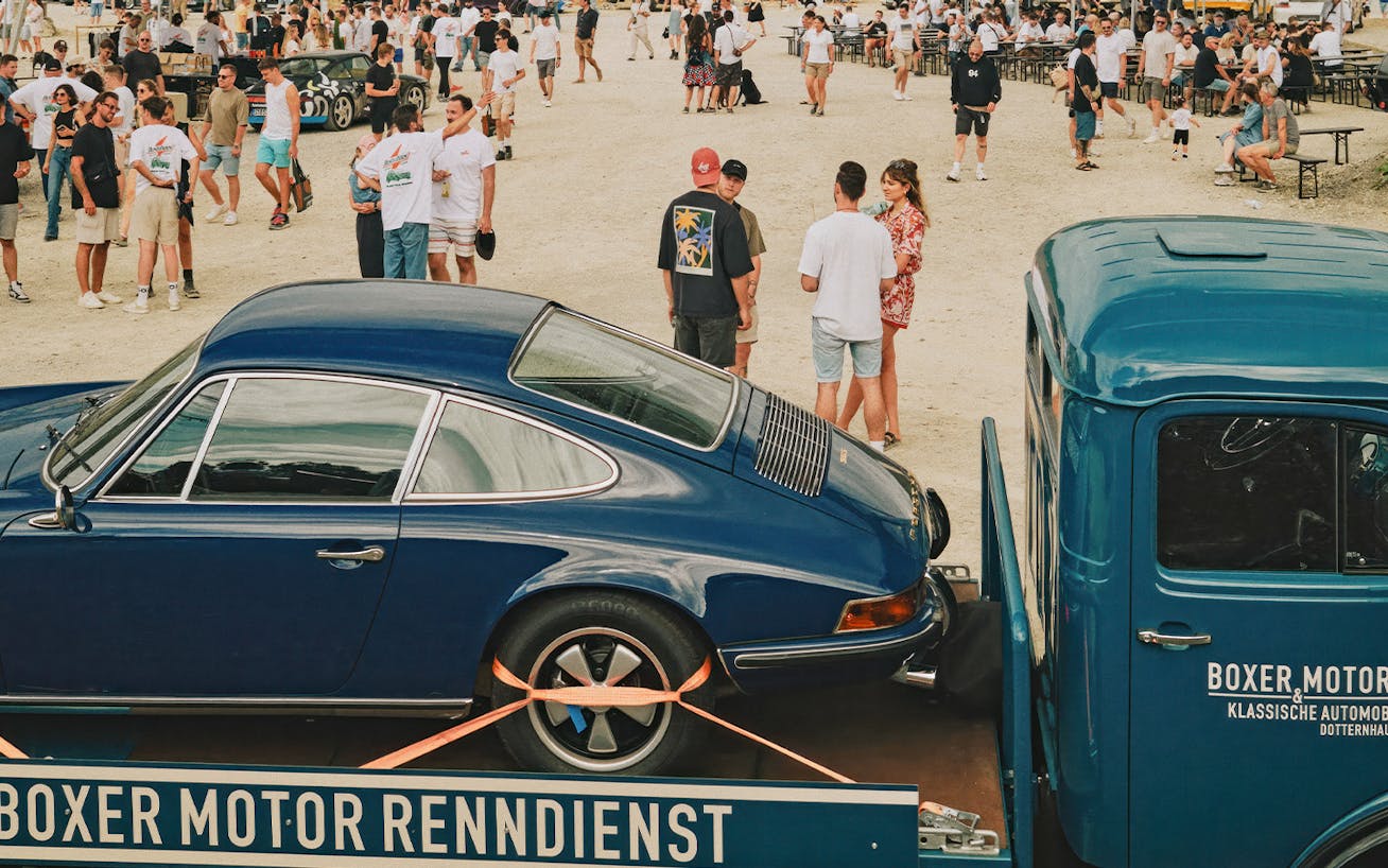 Classic Porsche 911 on back of a classic flat-bed truck at Heizr car community event