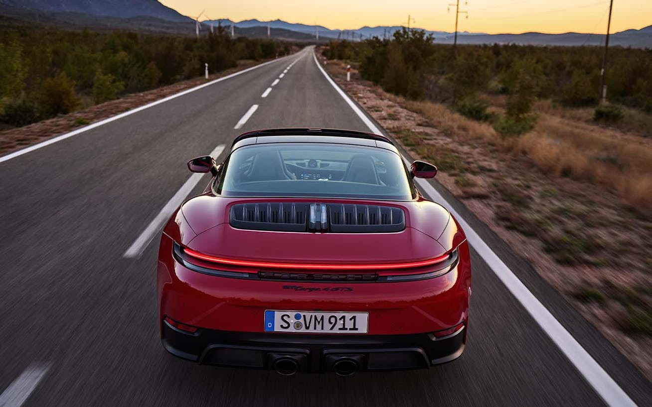 Porsche 911 Targa 4 GTS in Carmine Red driving on road at sunset