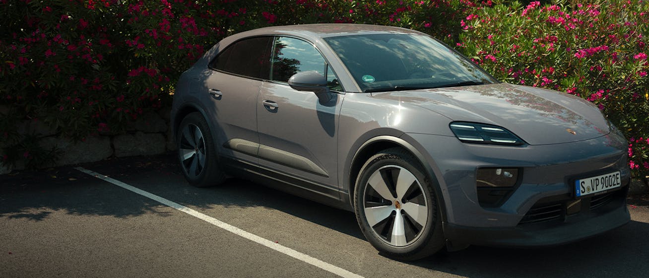 Porsche Macan 4 Electric in car park, surrounded by bougainvillea