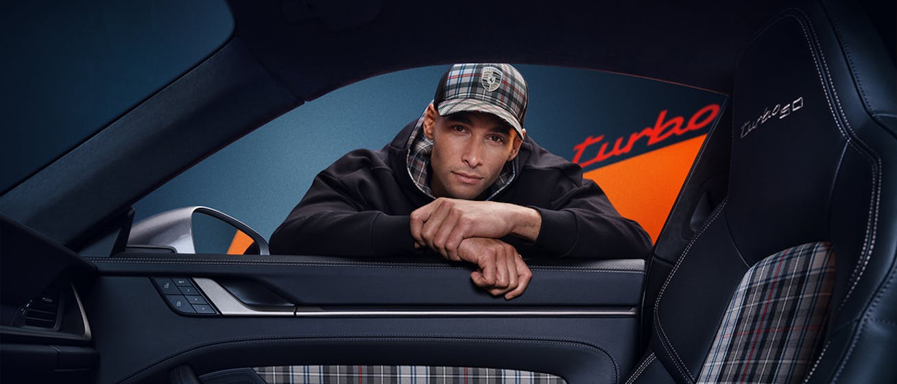 Man leaning into car window wearing tartan cap 