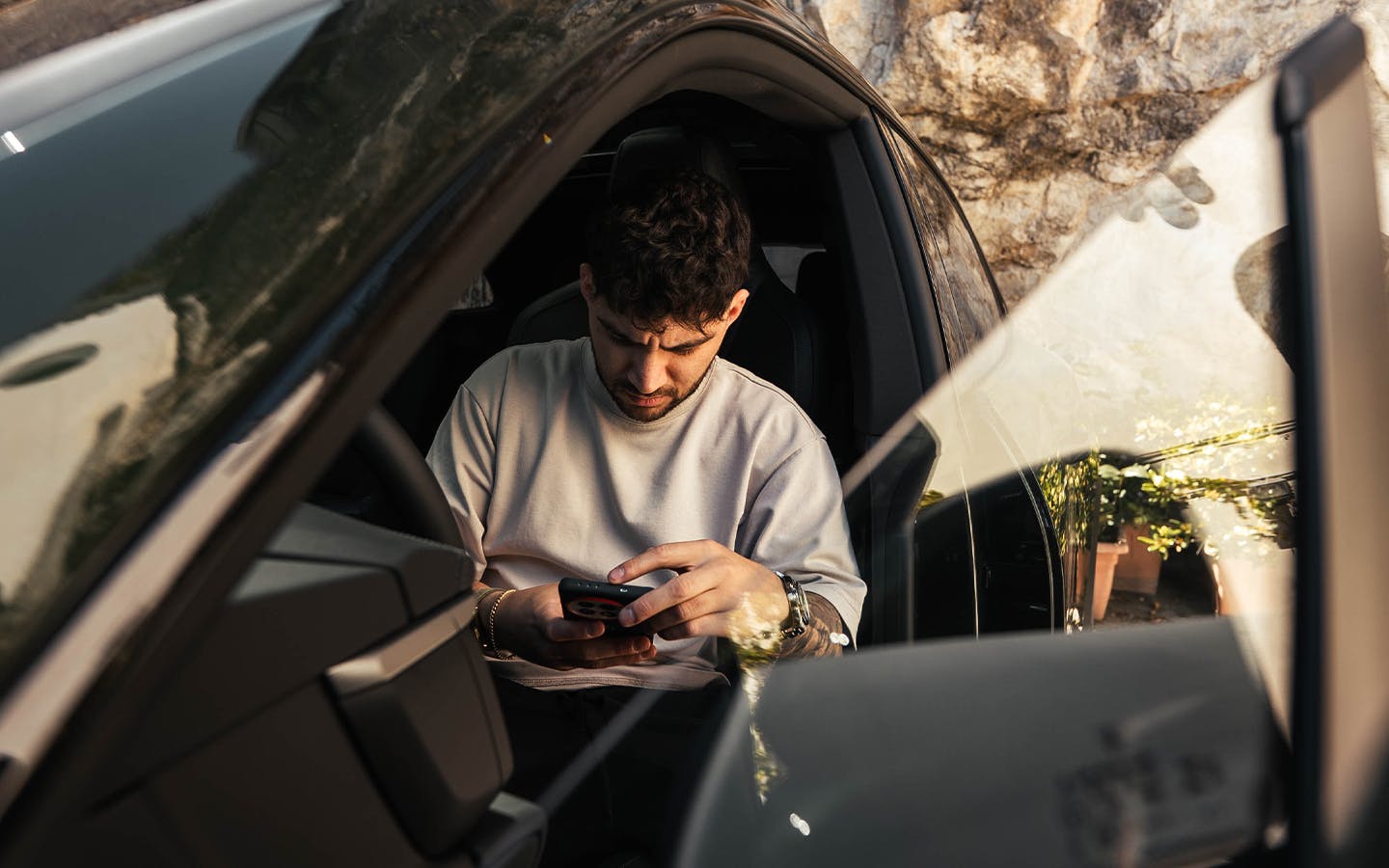 YouTuber Andres Vidoza checking phone in Porsche Macan 4S Electric