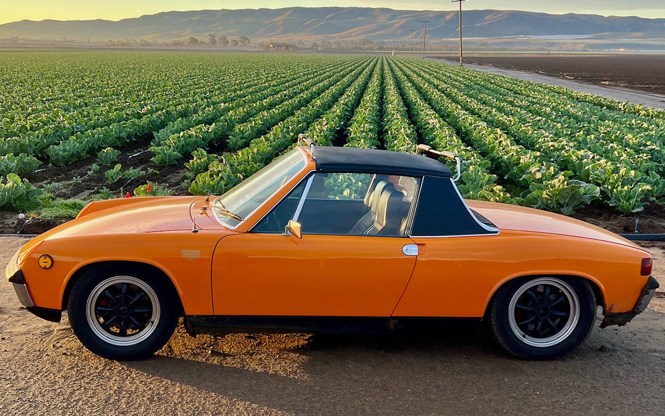 Side view of Signal Orange Porsche 914 with fields in background