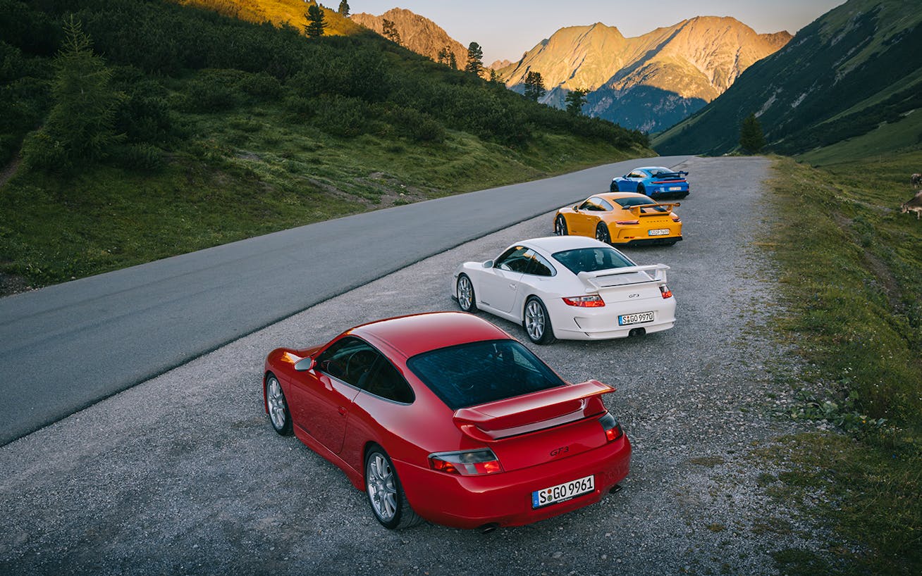 Four generations of Porsche 911 GT3 parked on mountain road