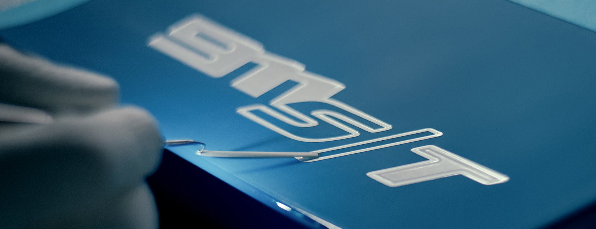 Hand applies name badge to Porsche Sonderwunsch 911 S/T sportscar