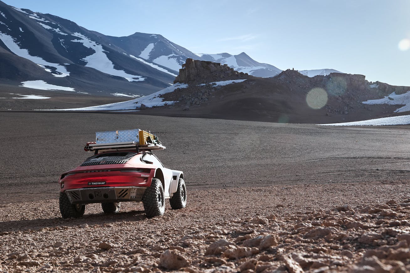 Off-road Porsche driving towards snow-capped volcano in Chile