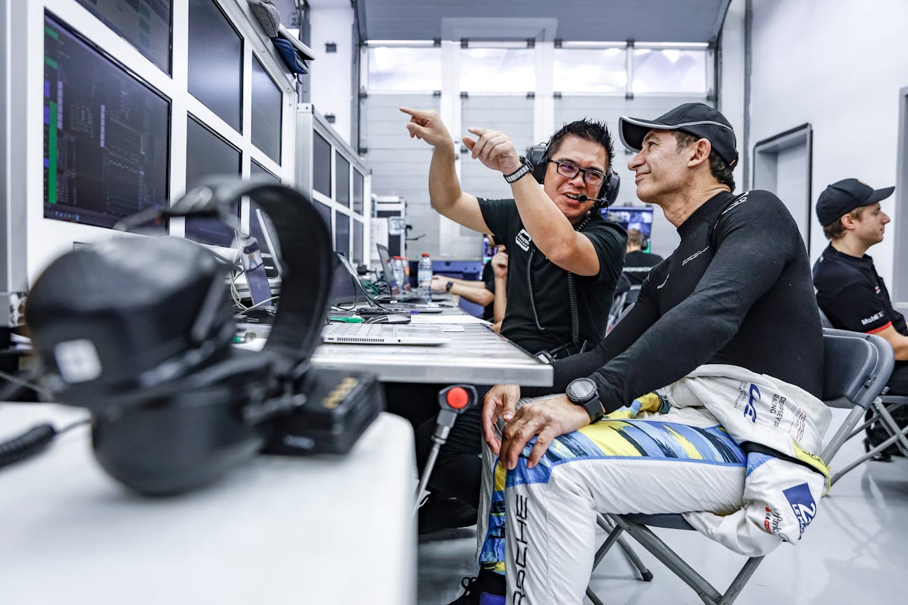 Race driver and data analyst sit in front of screen