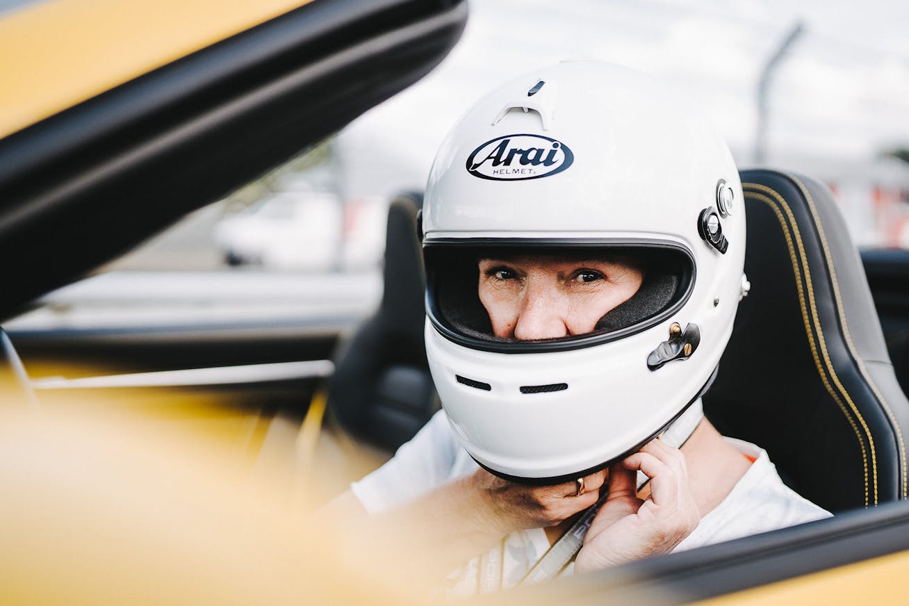 Woman with racing helmet in yellow Porsche 911 Turbo S Cabriolet