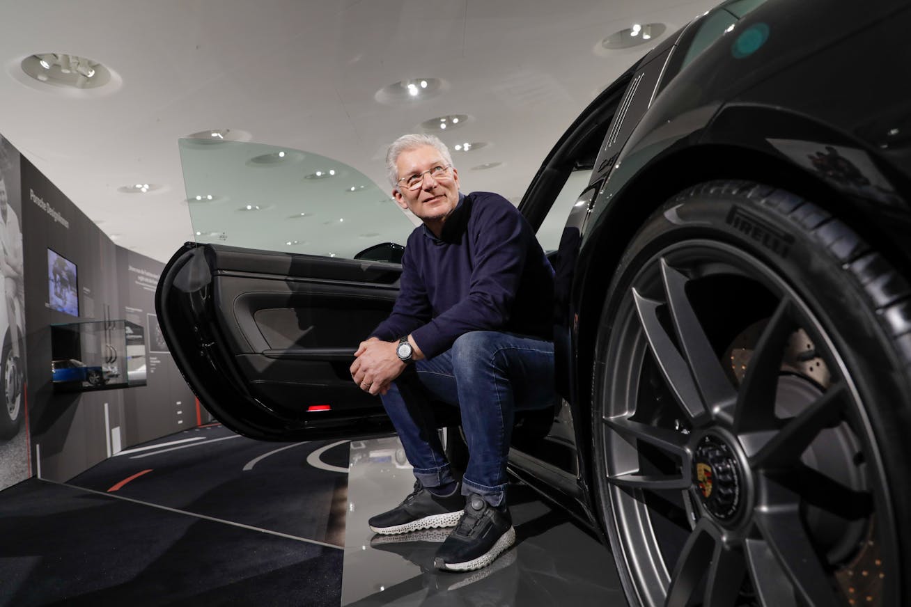 Man sits facing out of black Porsche 911 in museum