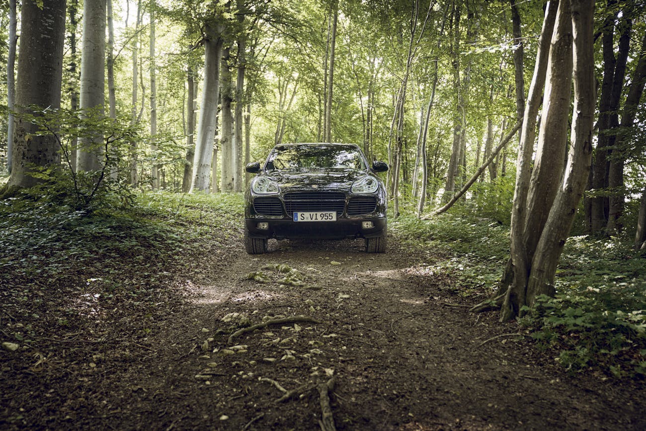 Green first-generation Porsche Cayenne in the woods