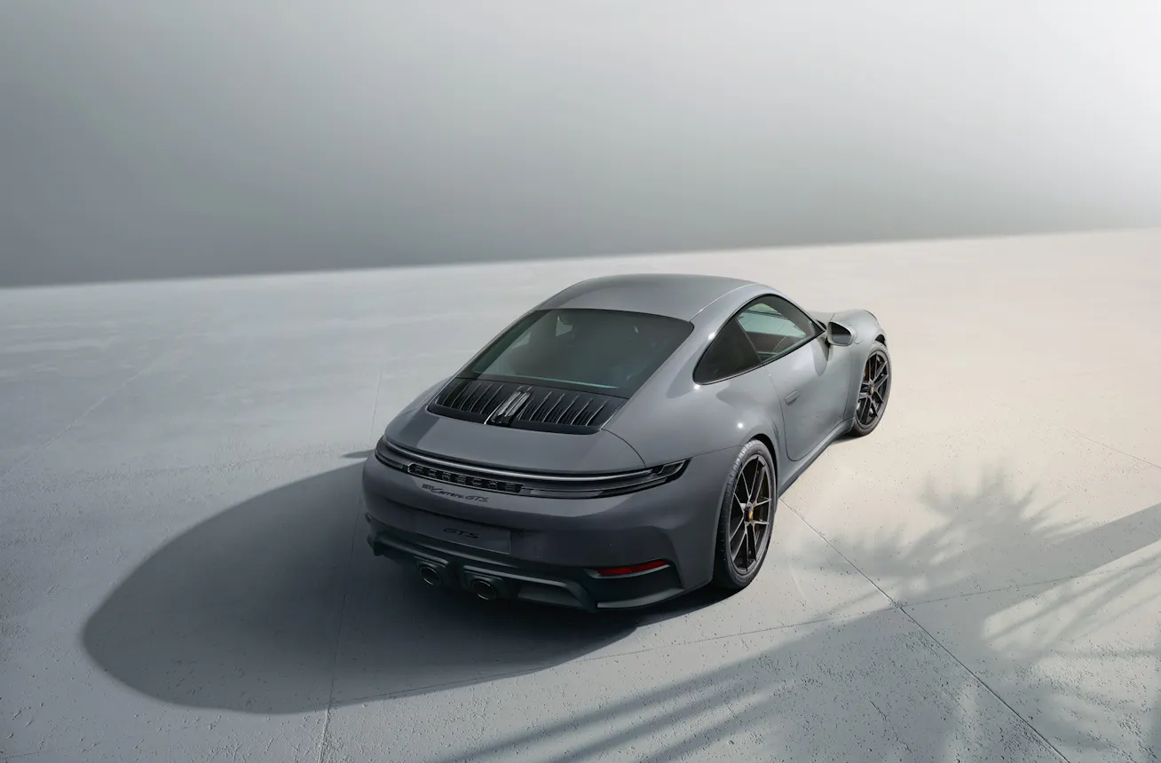Porsche 911 parked in studio landscape with reflections of trees in foreground