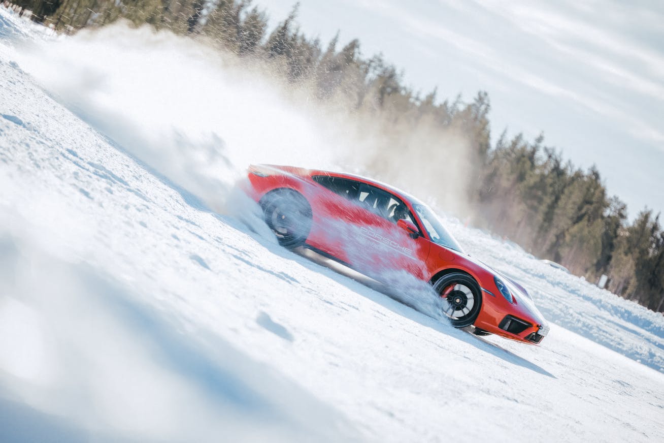 Red Porsche 911 driving dynamically over snow and ice on Porsche Ice Experience