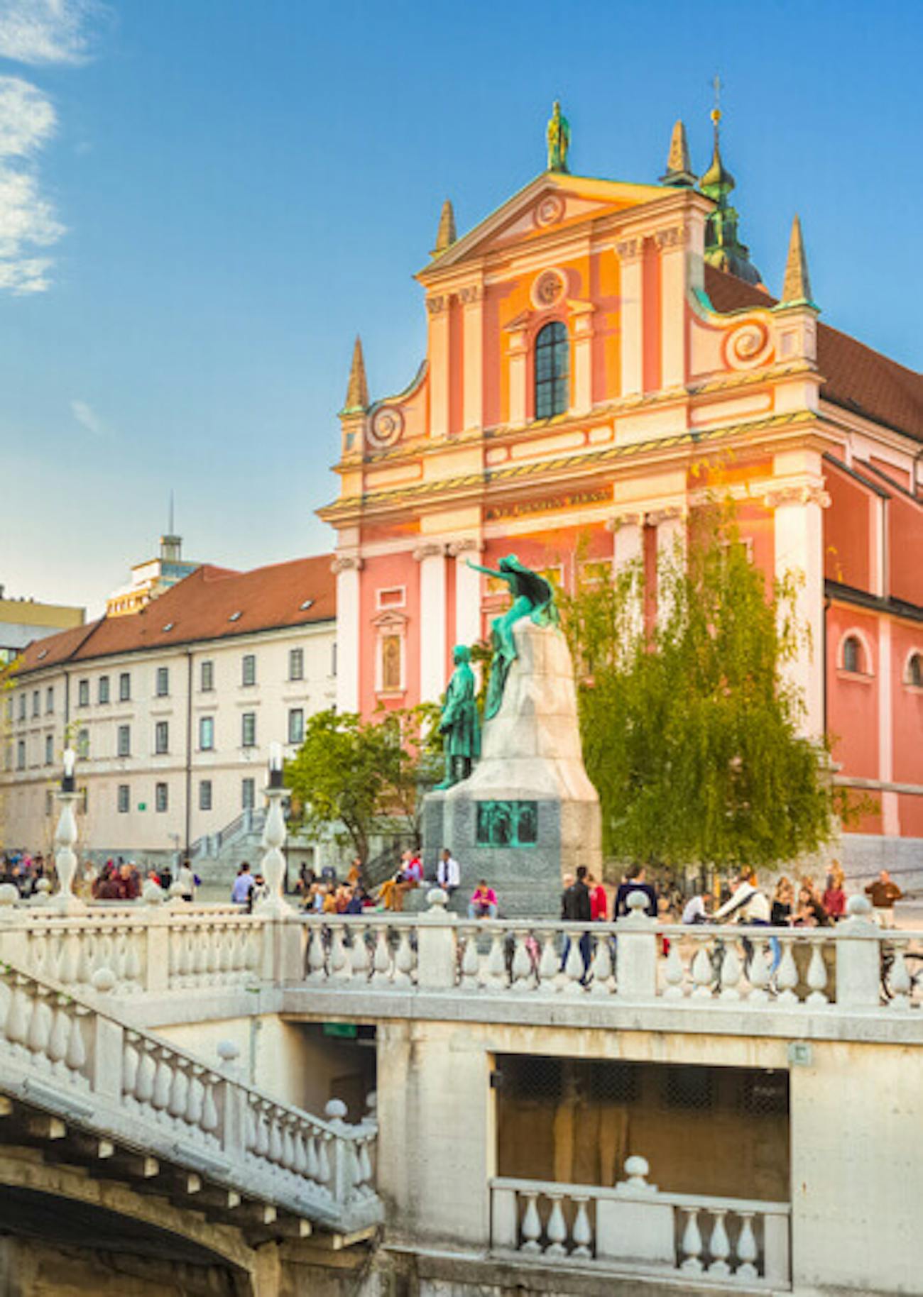 Pink-coloured Baroque church with statue in front in Ljubljana, Slovenia