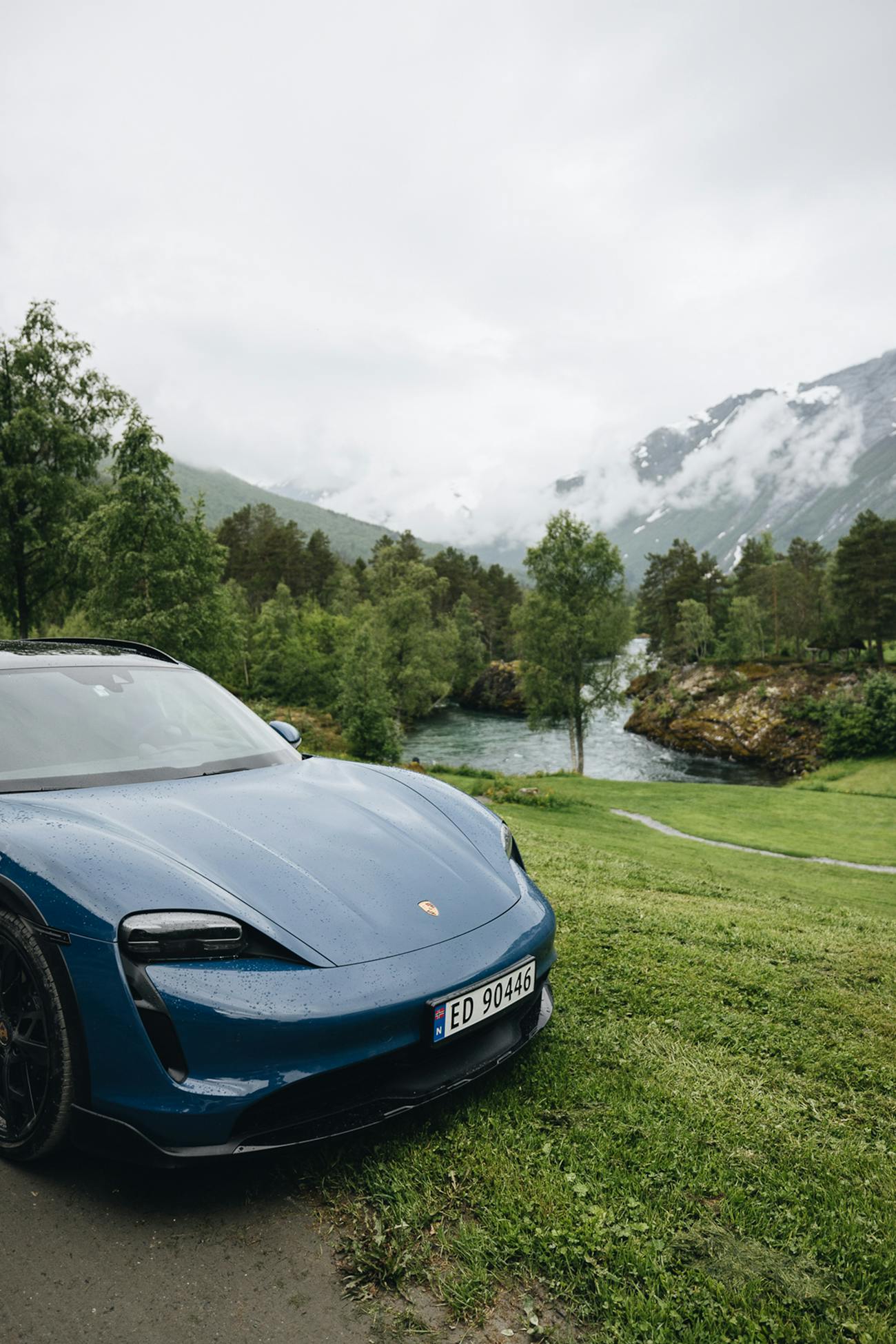 Blue Porsche Taycan Cross Turismo in Norwegian fjord land scene