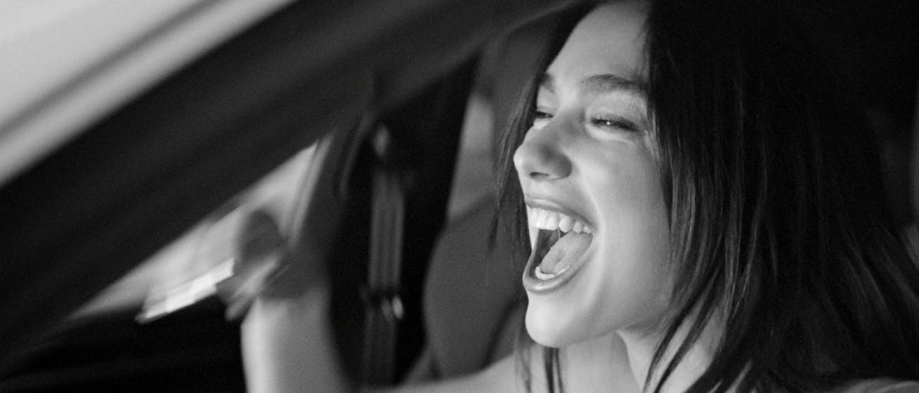 Monochrome photo of laughing woman having fun in car
