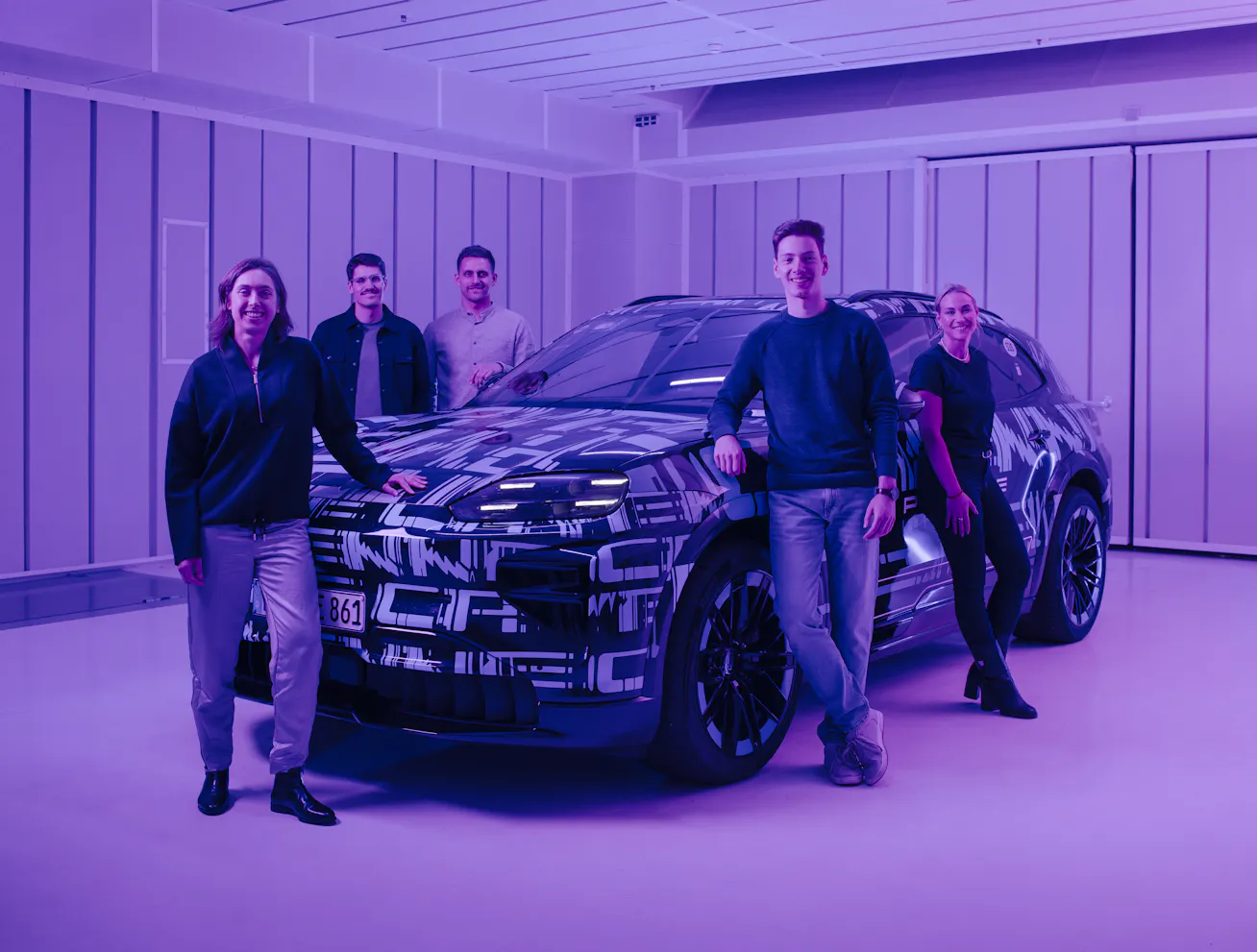 A group of people photographed beside a Porsche Cayenne Electric development vehicle