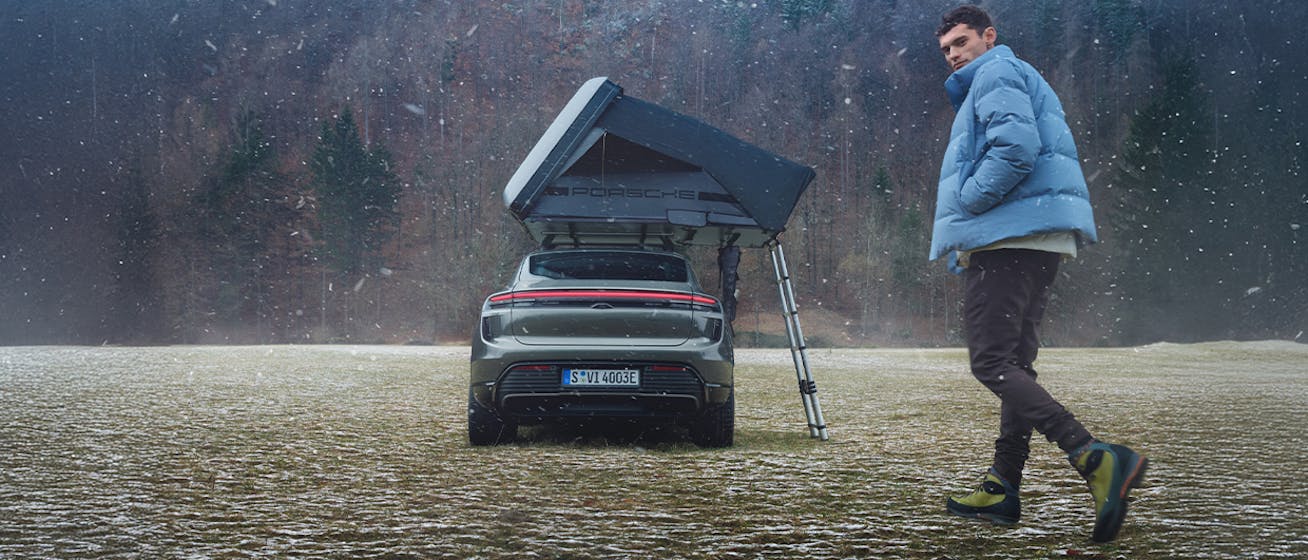 Rear of Macan Turbo electric with roof tent, man in foreground