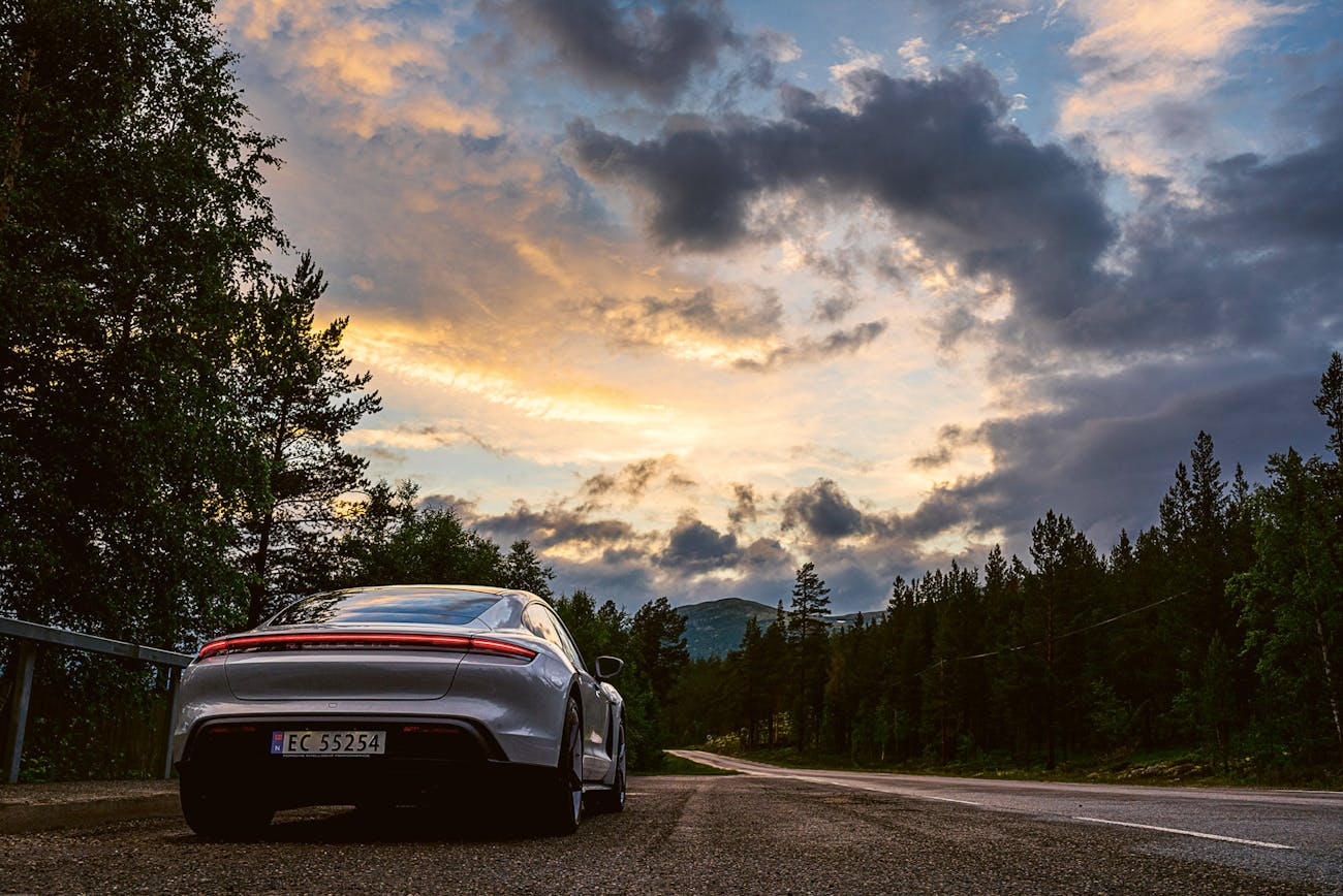 A silver Porsche Taycan drives through the Norwegian countryside