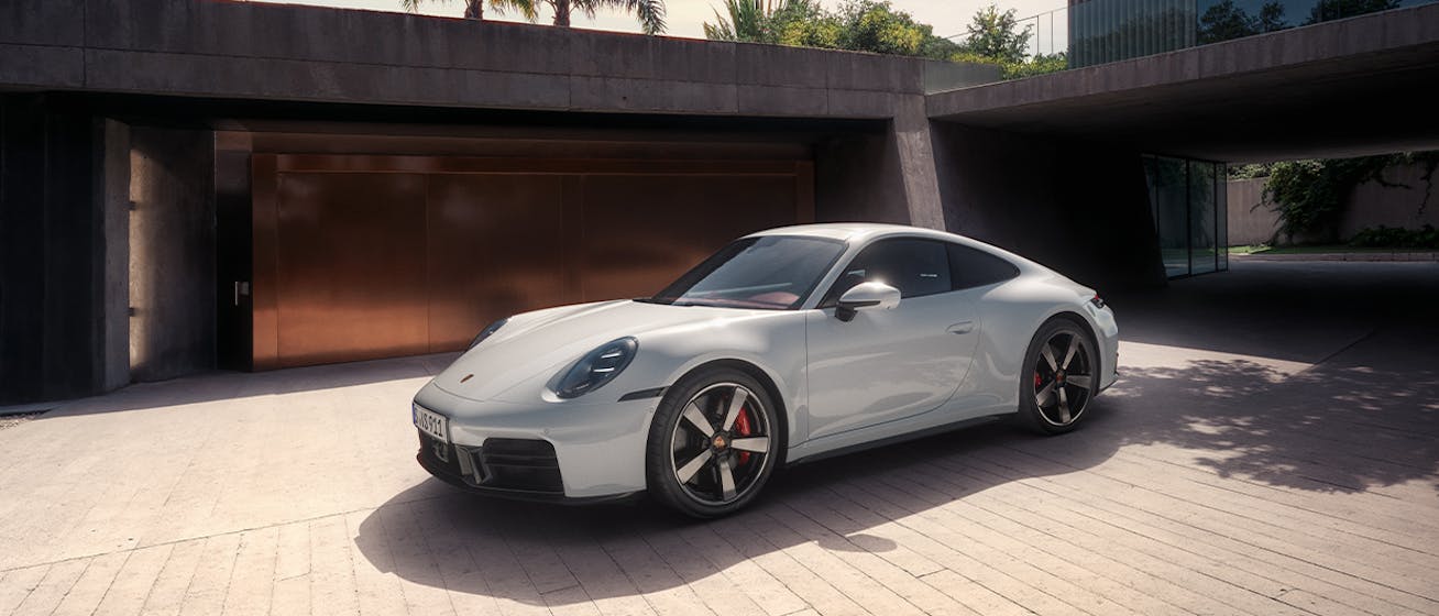 White Porsche 911 Carrera S parked outside modernist building