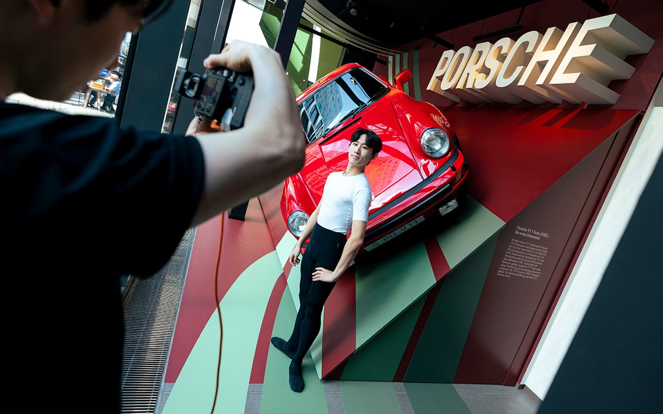 Male ballet dancer next to red Porsche 911 in Stuttgart