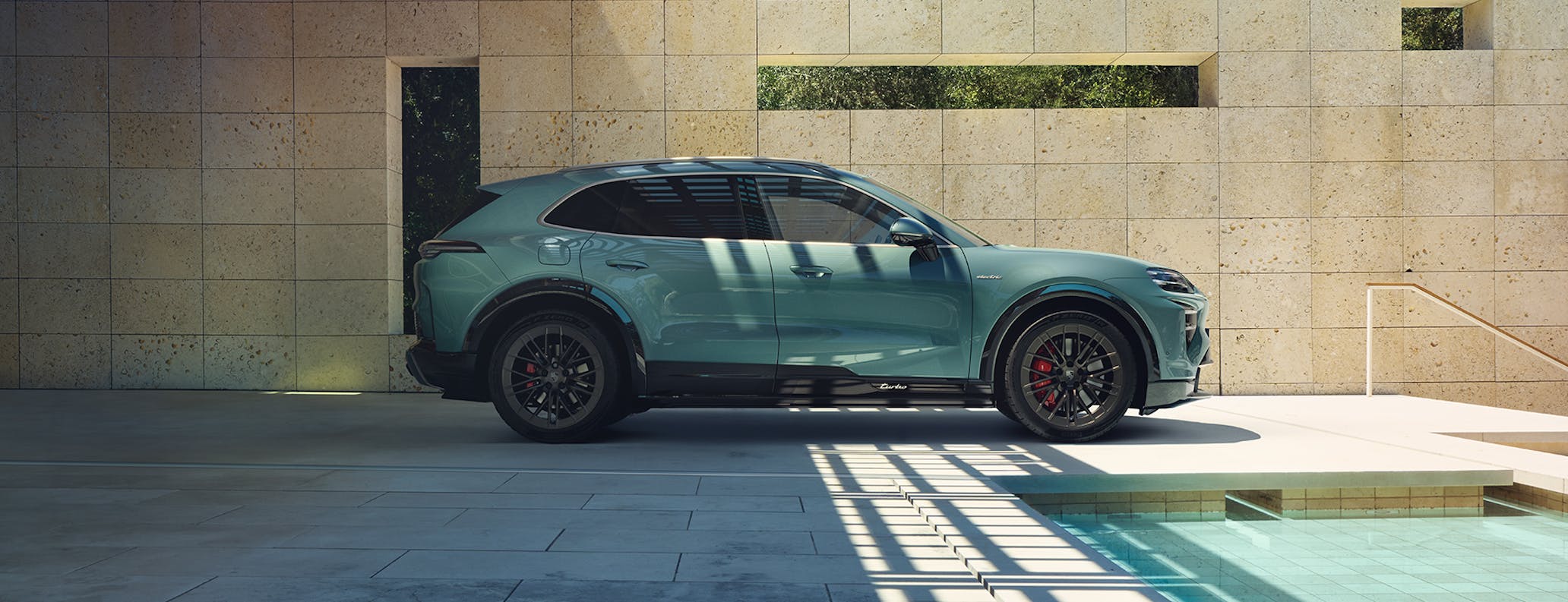 Side view of Porsche Cayenne Turbo Electric, partly in shade, partly in sunshine, parked next to swimming pool at modern house