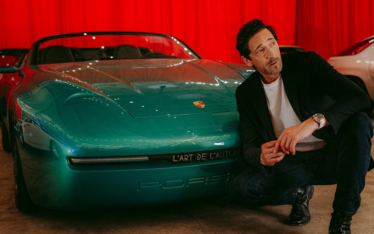 Adrien Brody crouches next to the Arthur Kar Porsche 968 L'ART at 2025 Goodwood Festival of Speed