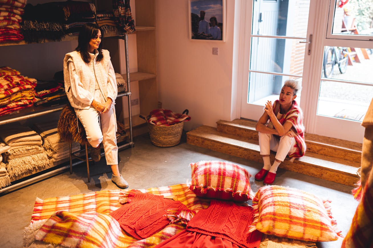 Two women in design studio, throws and cushions on floor