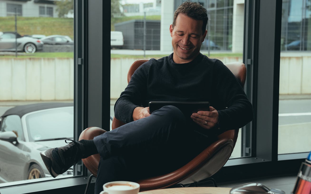 Smiling man sitting in chair holding iPad by office window