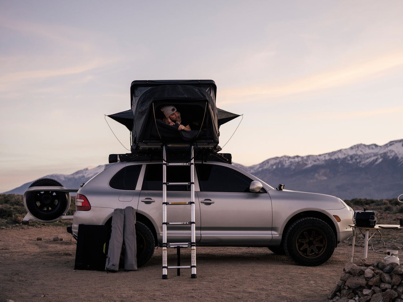 Women leaning out of roof-top tent on Porsche Cayenne