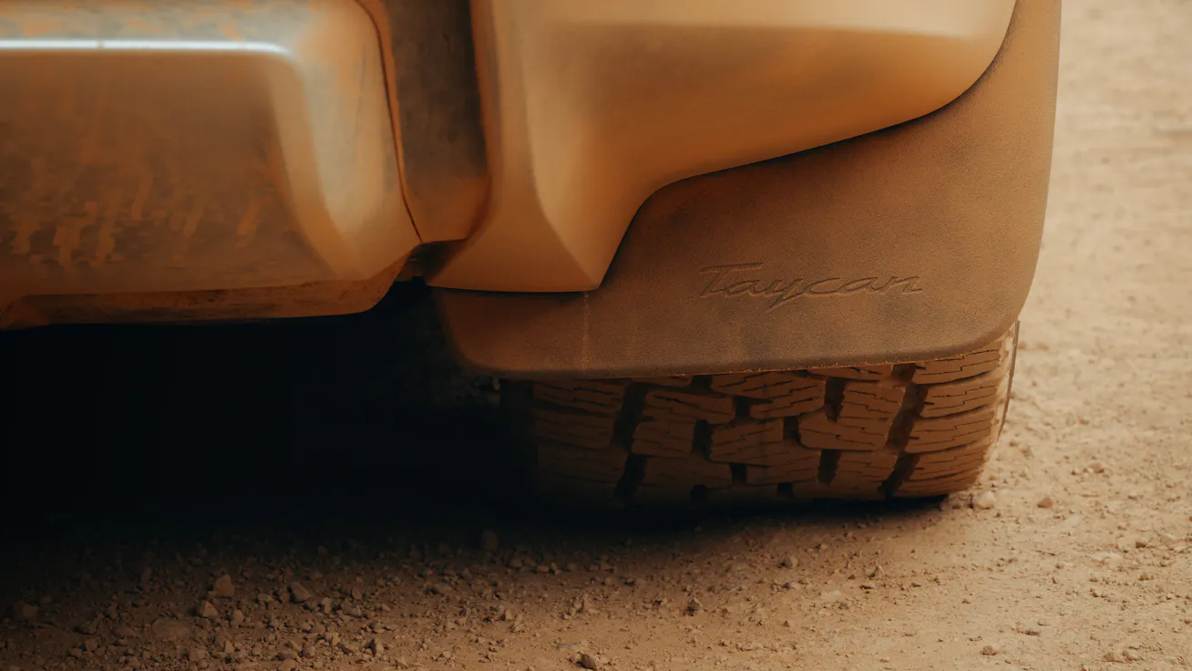 Close-up view of Porsche Taycan Cross Turismo fitted with Adventure Accessories showing mud flaps with Taycan embroidered  