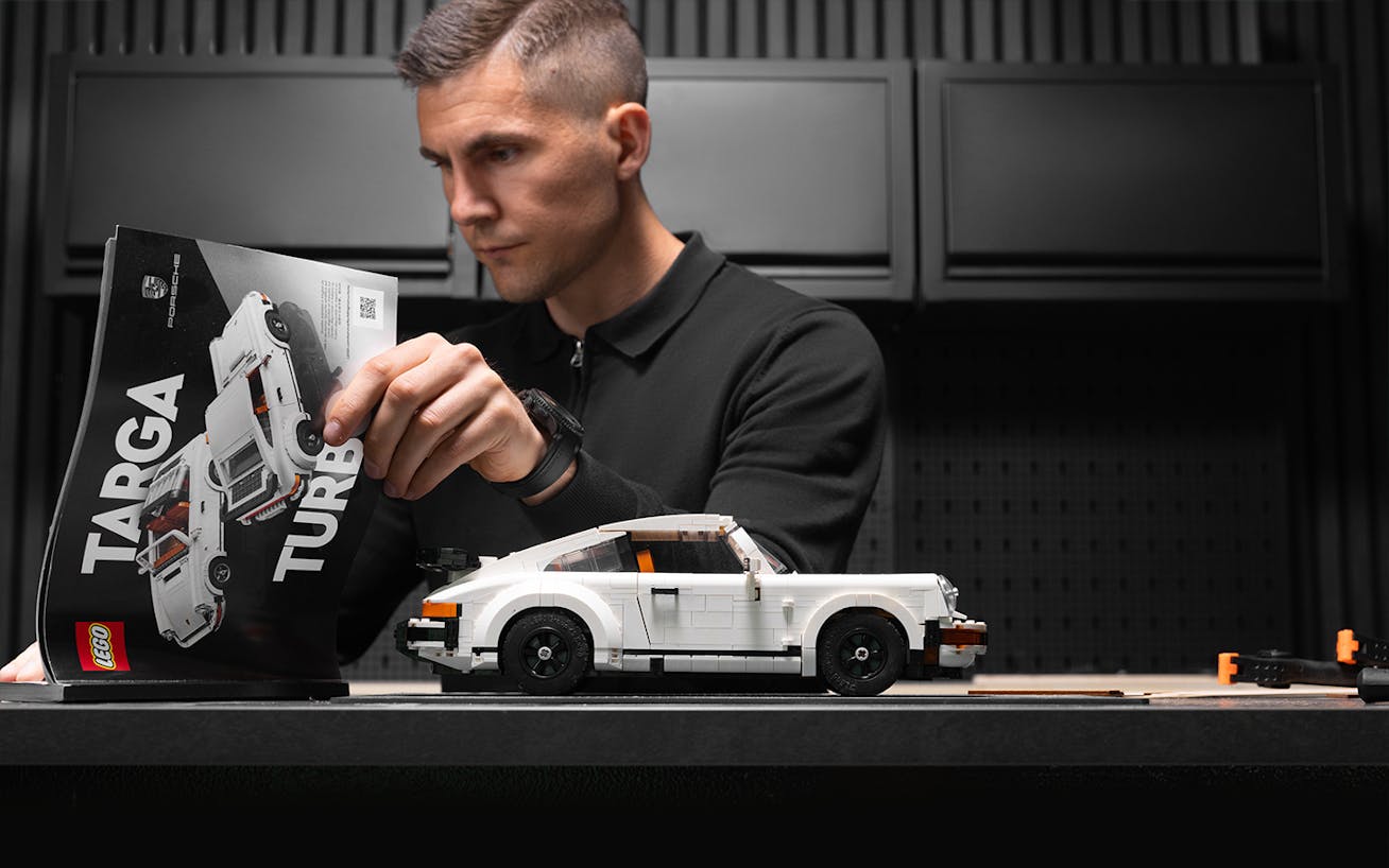 Man reading manual for building LEGO Porsche 911 Turbo