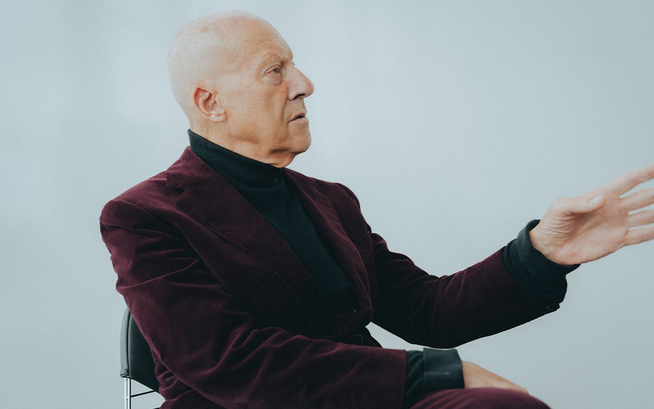 Lord Norman Foster, in burgundy velvet suit, gesturing during interview